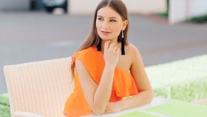 A Beautiful Woman in Orange Top Sitting on a Chair