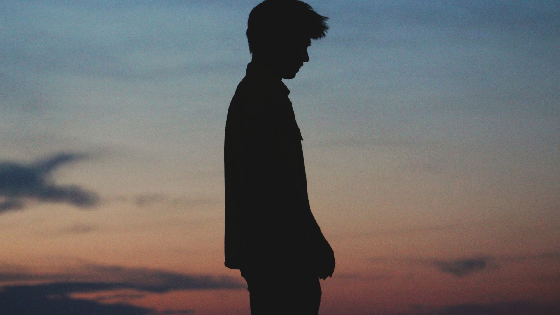 A Silhouette of a Man Standing in Side View