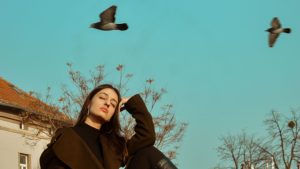 A Woman Posing Near Birds Flying