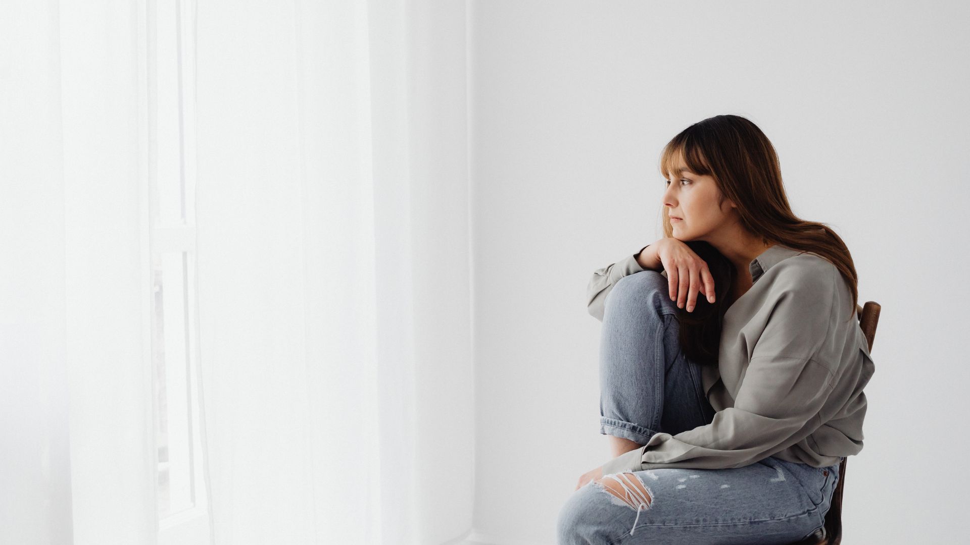 A Woman in Gray Long Sleeves Sitting on Chair Looking Pensive