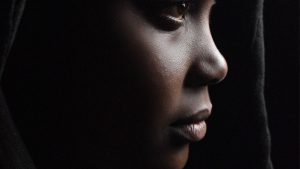 Crop pondering black woman in dark room