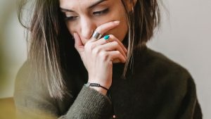 Lady crying with hand on mouth in room