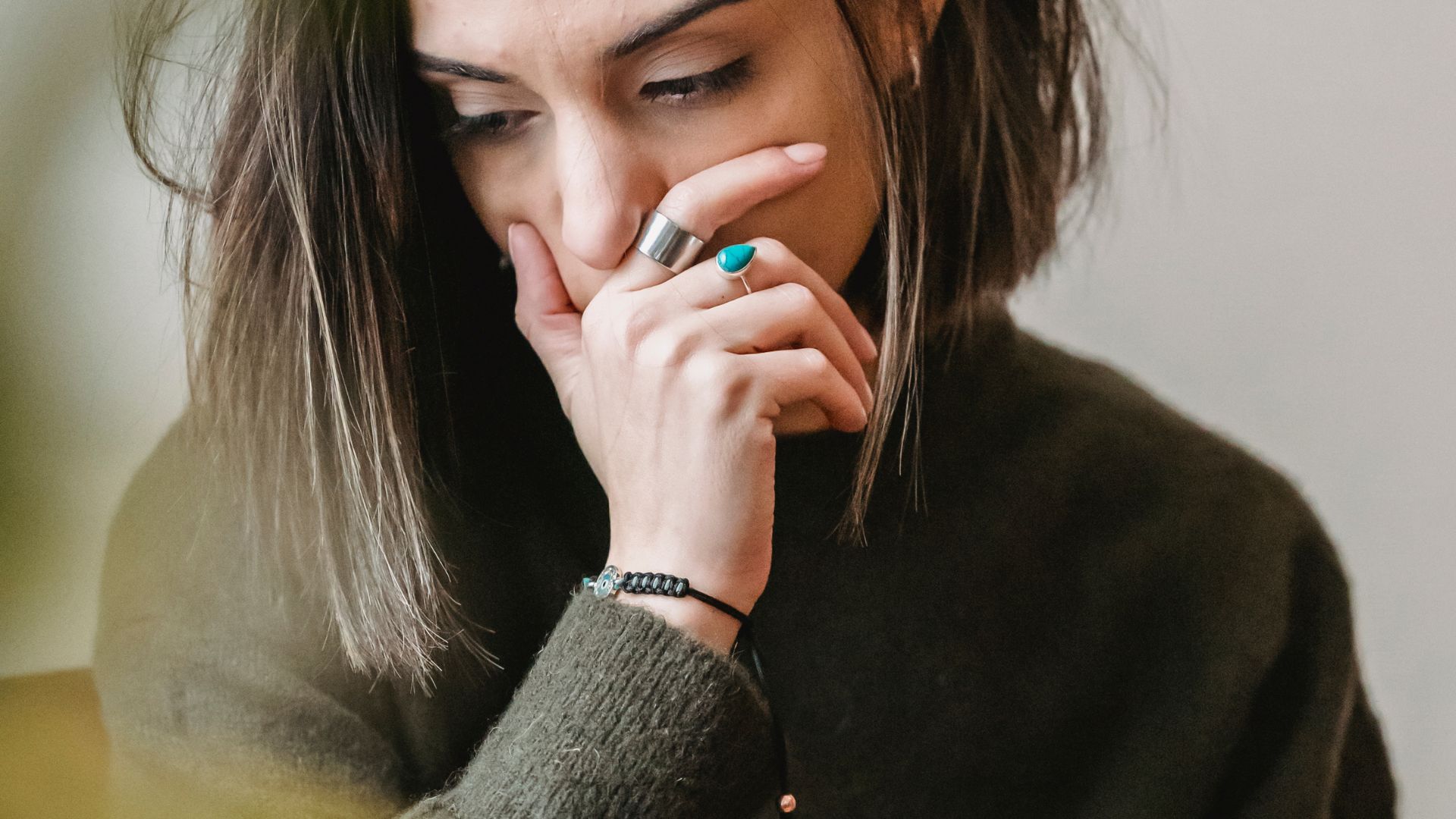 Lady crying with hand on mouth in room