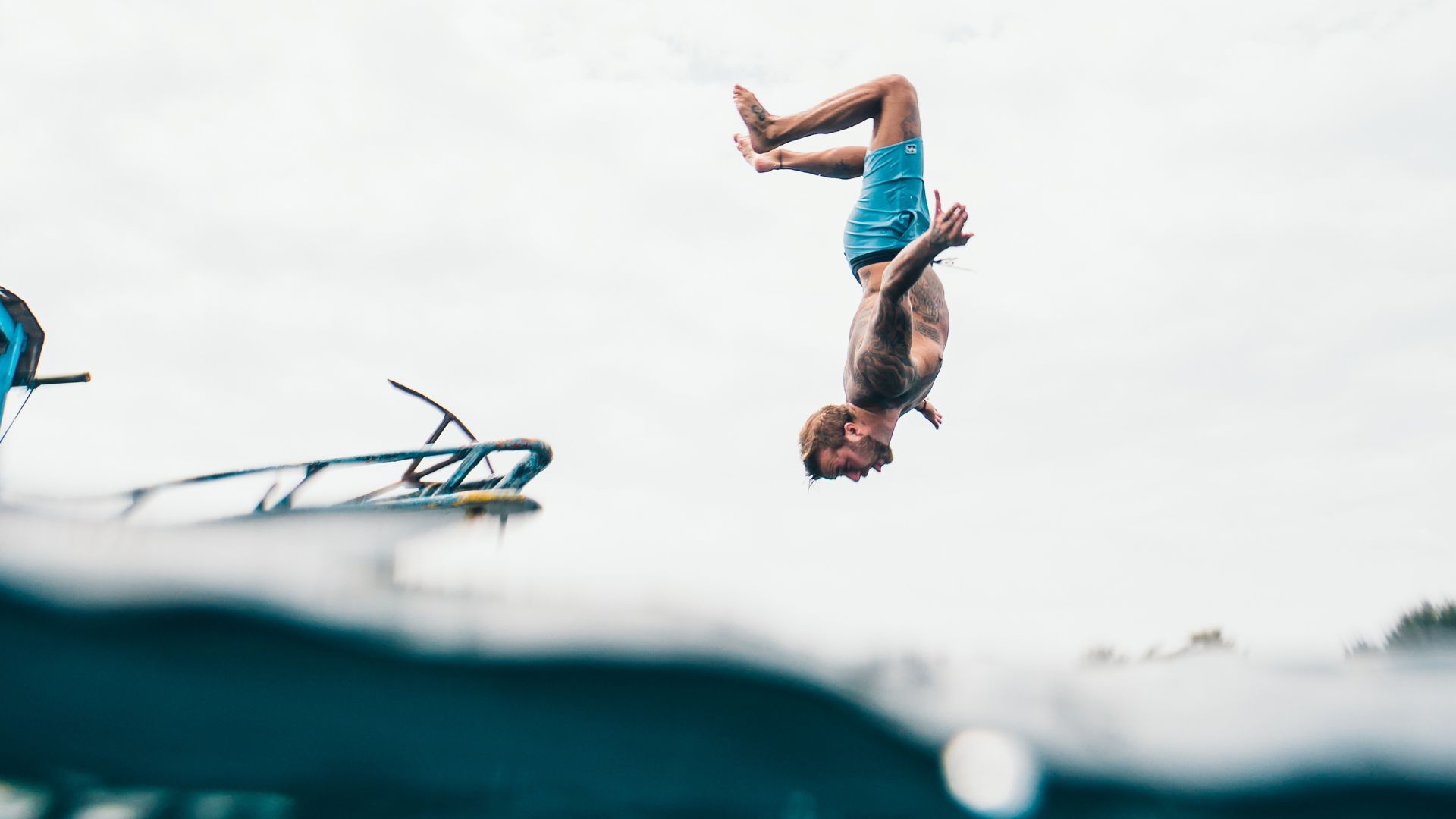 Man Wearing Blue Shorts About to Dive on Body of Water