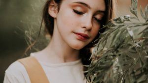 Mindful teen against shrub branch in park