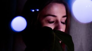 Mindful woman covering mouth in evening lights
