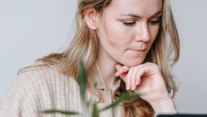 Pensive woman browsing laptop in room