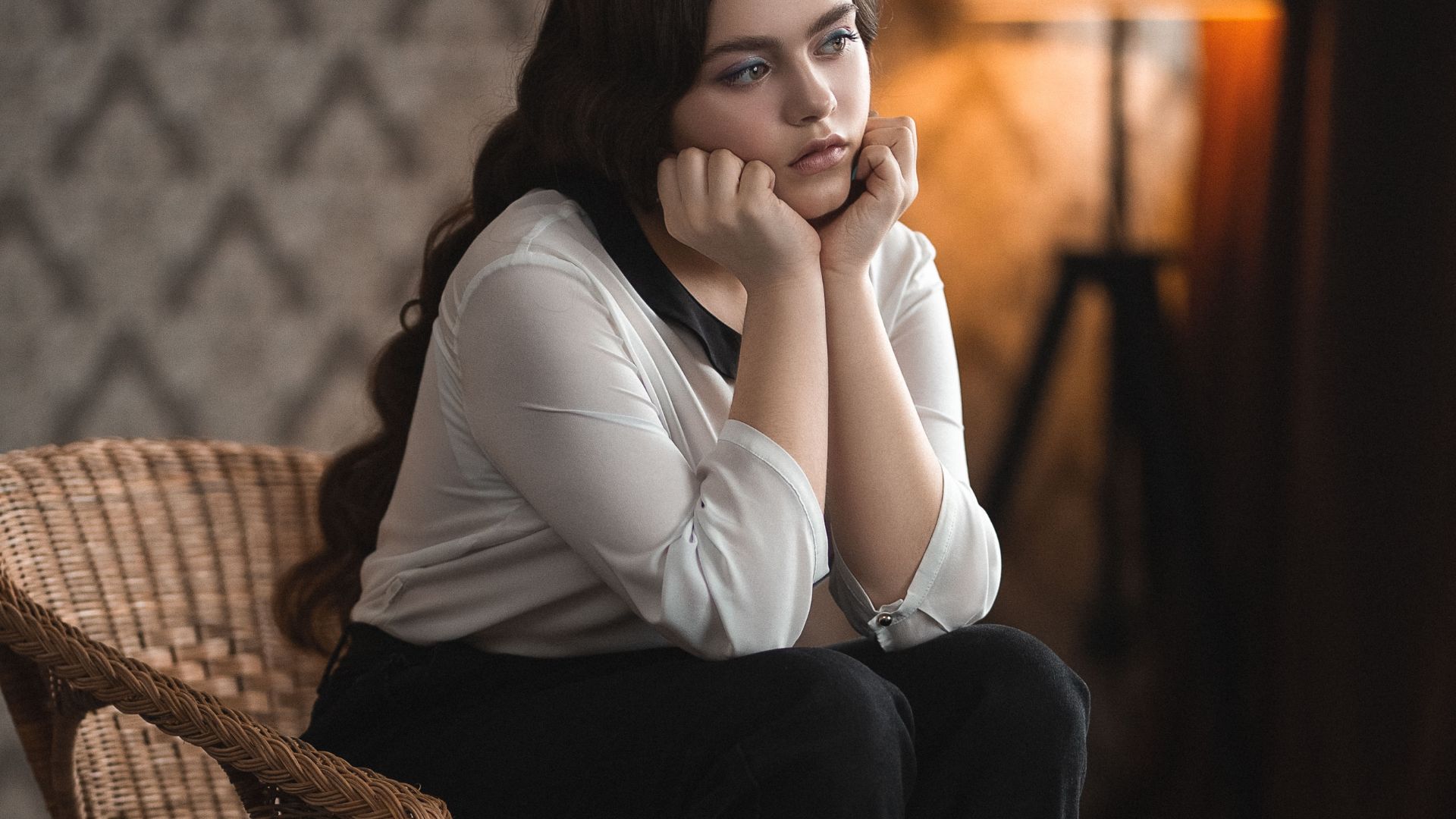 Pensive woman sitting on chair in room