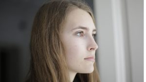 Pensive young woman in living room