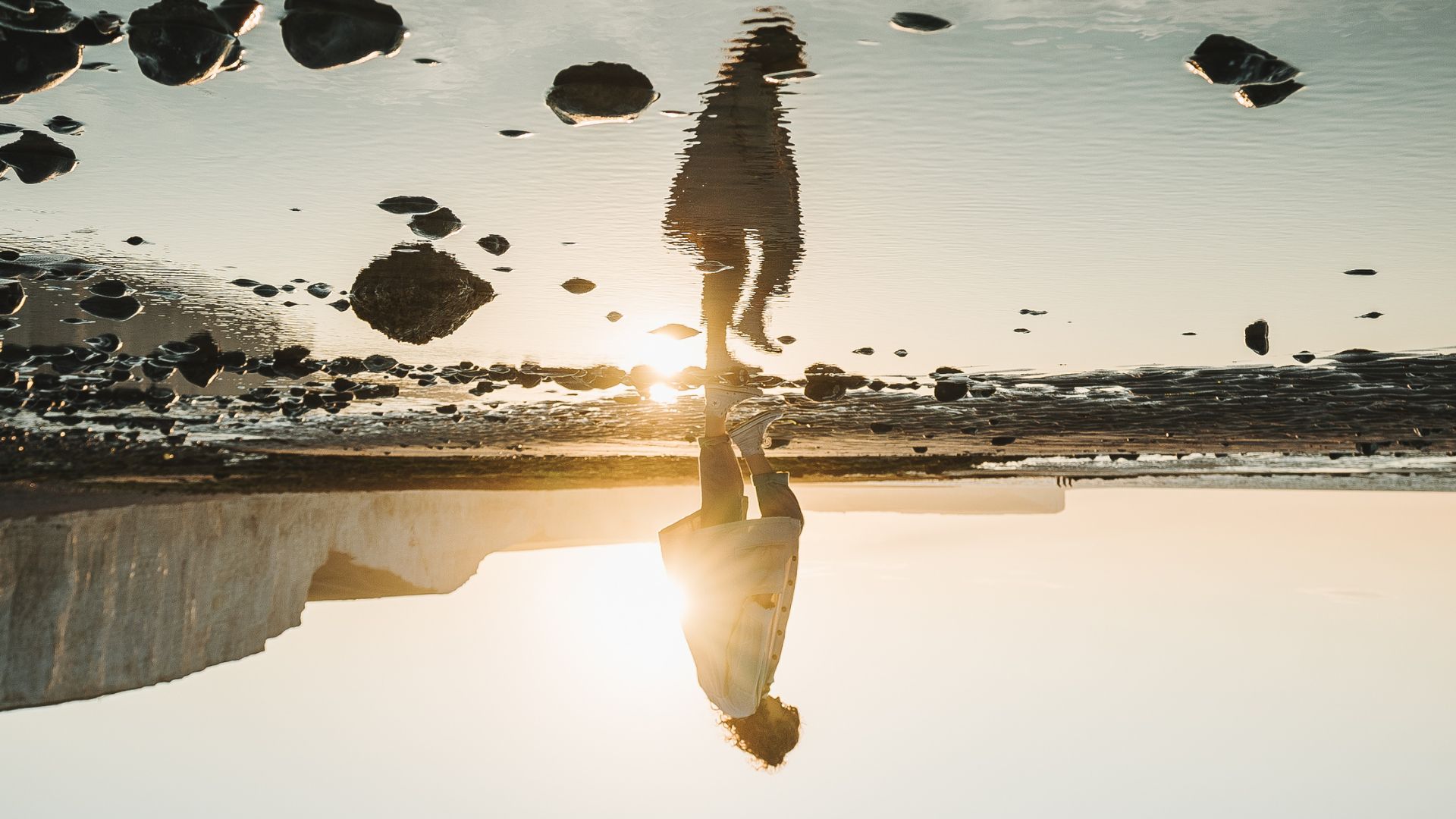 Reflection of person in puddle with stones