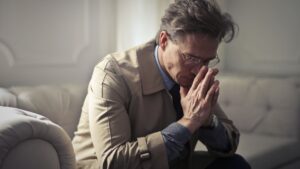 Sad mature businessman thinking about problems in living room