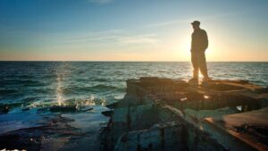 Silhouette Photo of Man Standing Near the Edge of Concrete Pavement