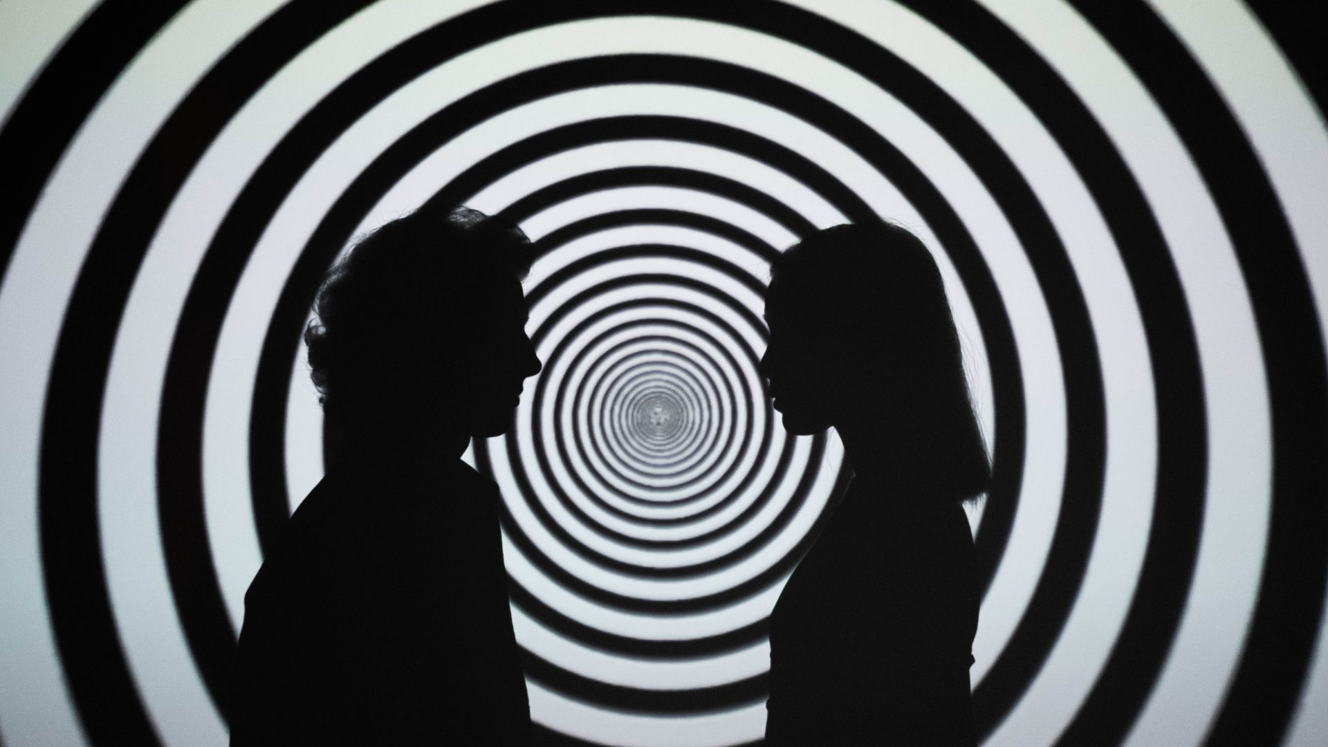 Silhouette of 2 Person Standing in Front of White and Black Stripe Wall