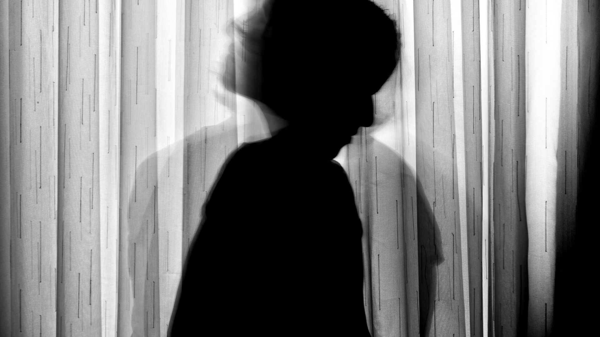 Silhouette of Person Standing Near Window Curtain