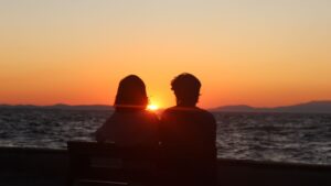 Silhouette of a Couple Sitting on Bench in Front of the Sea during Sunset