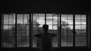 Silhouette of a Person Standing in Front of a Window