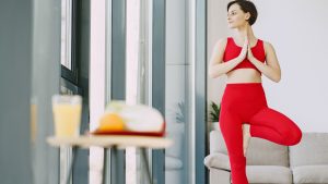 Slim woman doing yoga exercise in living room