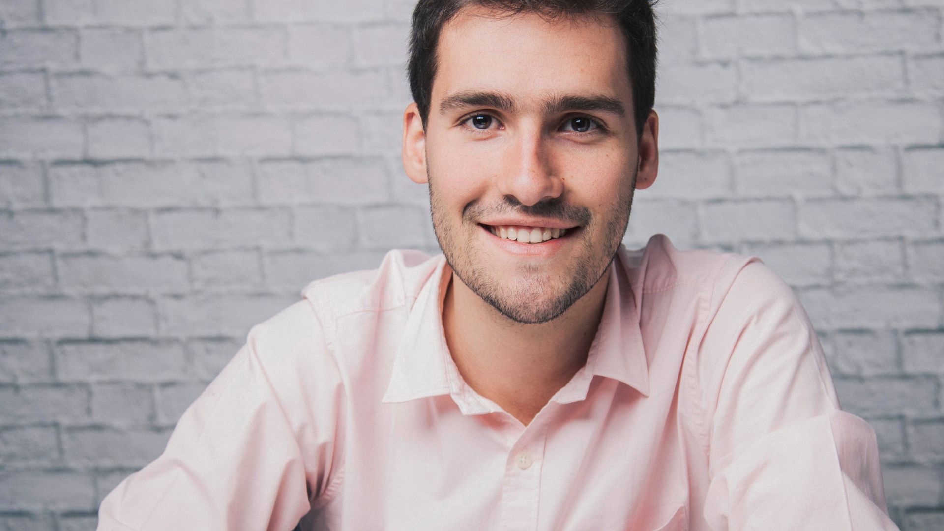 Smiling man sitting at table and crossing arms