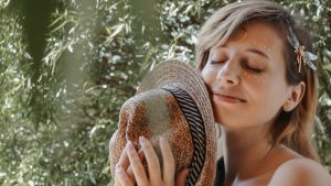 Smiling mindful woman with hat in garden