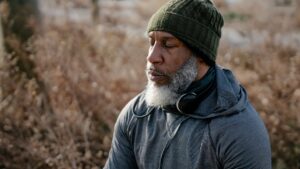 Thoughtful black man in activewear meditating in nature