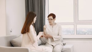 Two Women in White Clothes Sitting on Couch and Talking