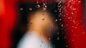 Window with water drops behind unrecognizable person