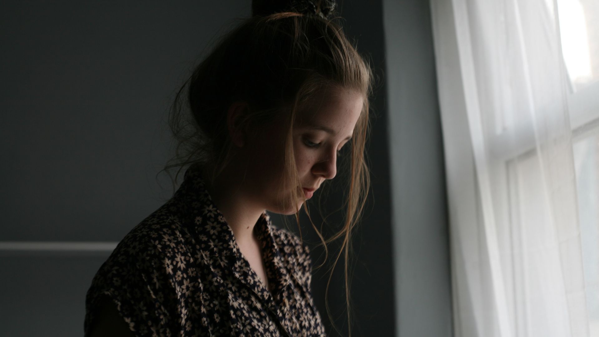 Woman Standing Beside Window Curtain