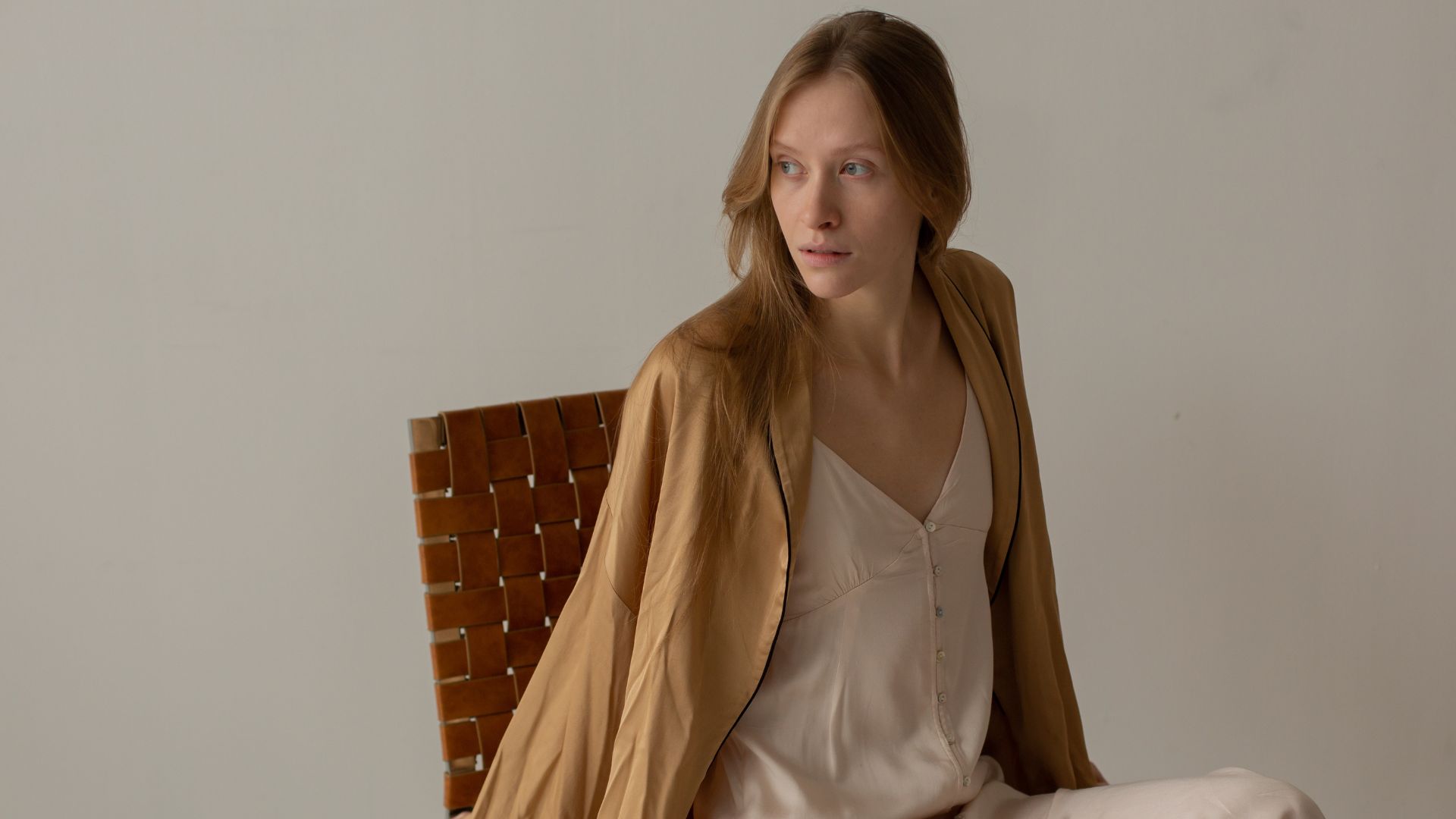 Woman in Beige Dress Sitting on Brown Chair