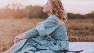 Woman in Blue Dress Sitting on Brown Grass Field