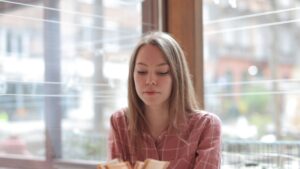 Woman in Pink and White Plaid Dress Shirt Sitting at Table