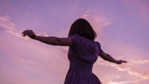 Woman in Purple Dress Raising Her Hands