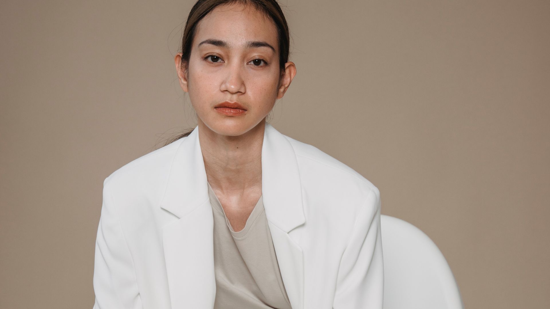 Woman in White Blazer Sitting on White Chair