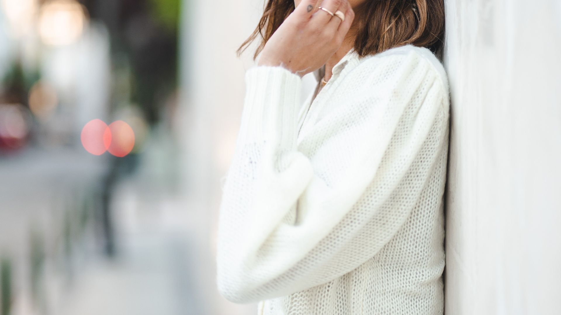 Woman in White Cardigan Leaning on Wall