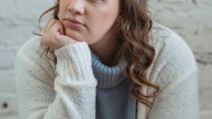 Young woman supporting head with hand and looking away