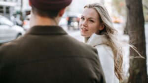 Young woman talking to man on street